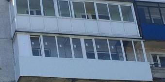 Длинный балкон с обшивкой пластиковыми панелями и остеклением